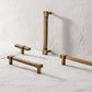 Three brass cabinet handles on a light gray surface with a white textured wall background